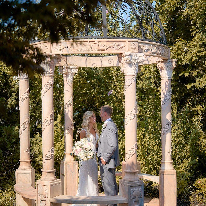 A bride and groom are standing under a gazebo.