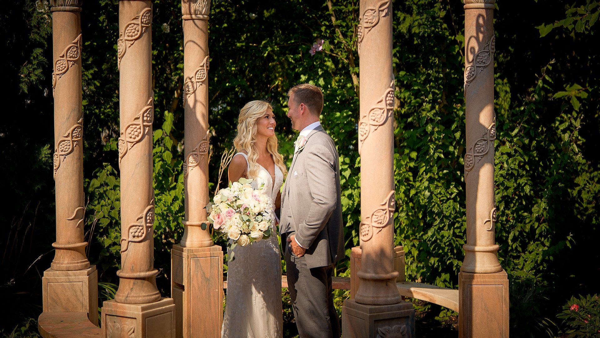A bride and groom are standing next to each other under a gazebo.