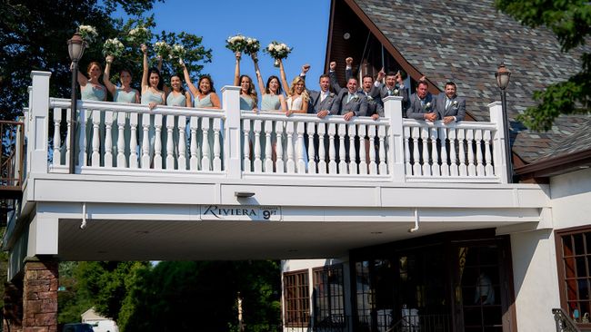 a group of people standing on a balcony holding flowers .