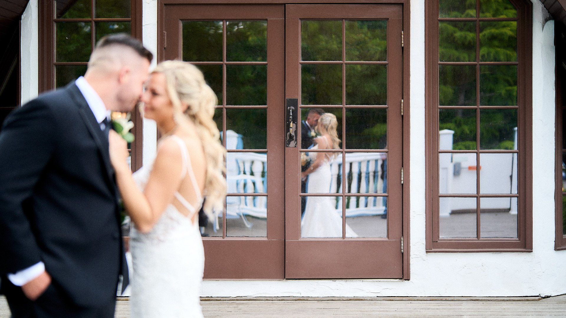 A bride and groom are kissing in front of a building.