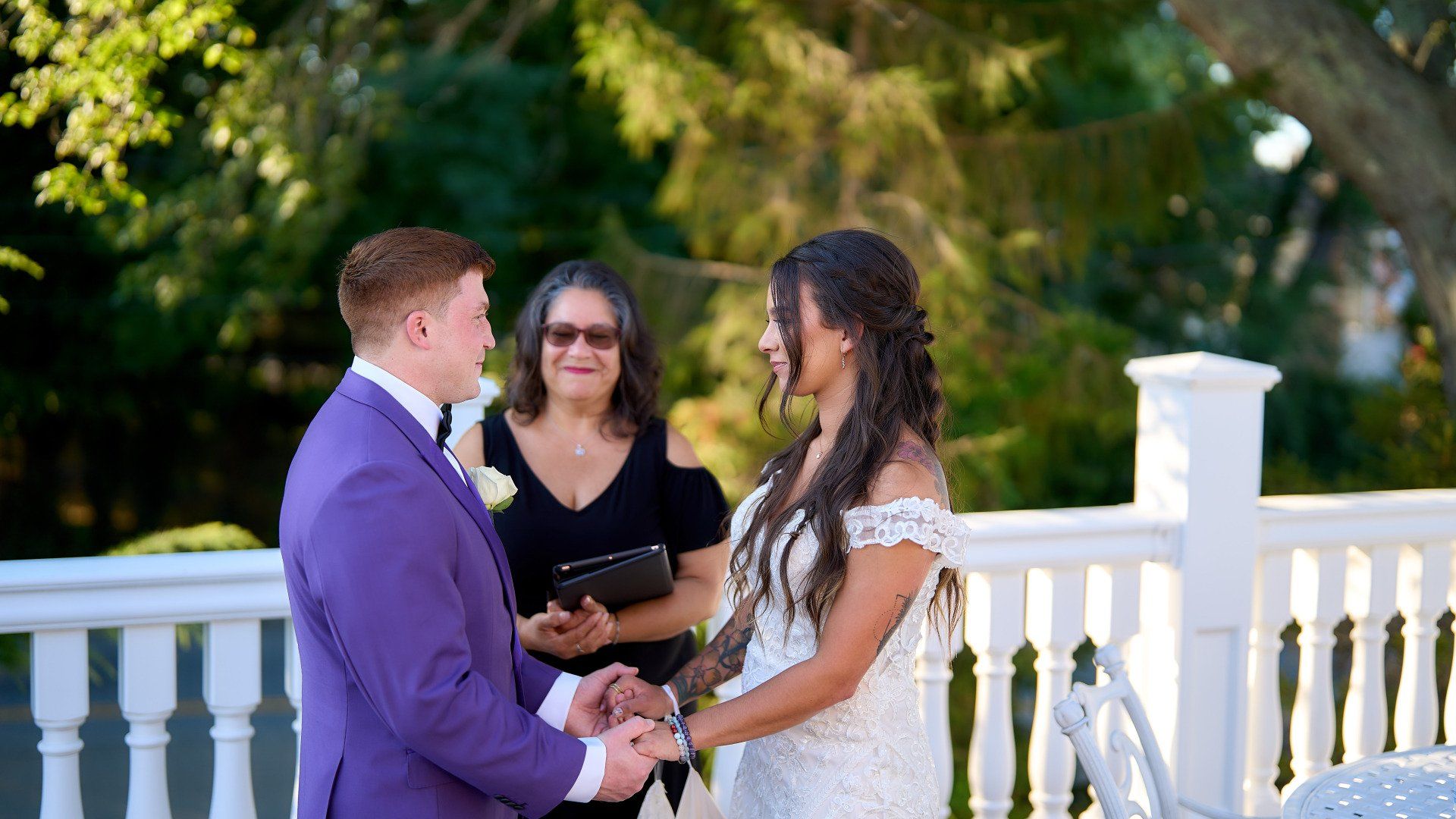 A bride and groom are holding hands during their wedding ceremony on a balcony.
