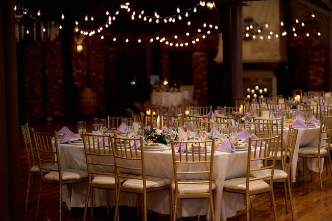 A room filled with tables and chairs set up for a wedding reception.