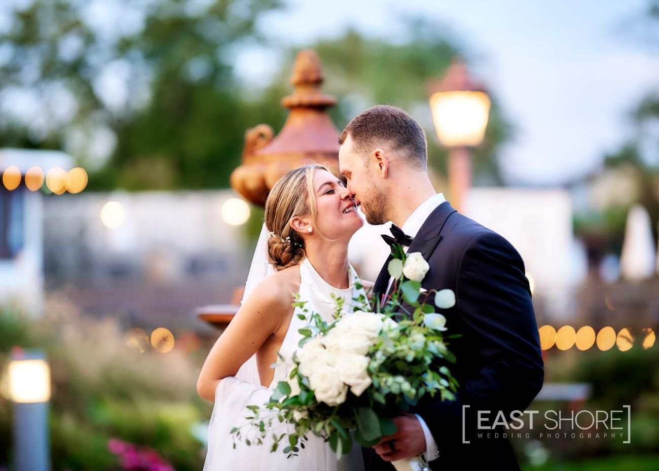 A bride and groom are posing for a picture in front of a fountain.