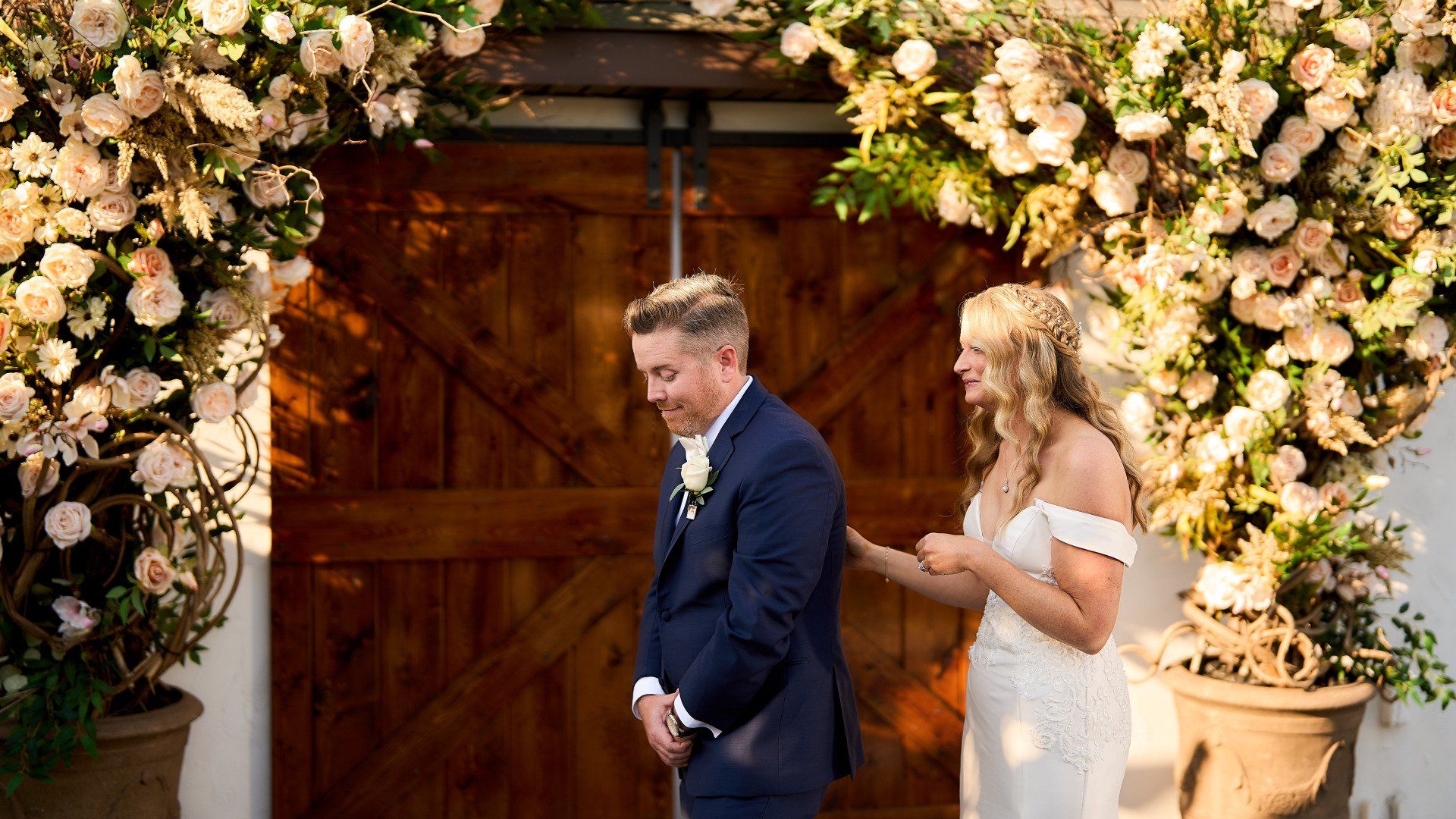 A bride and groom are standing in front of a wooden door.