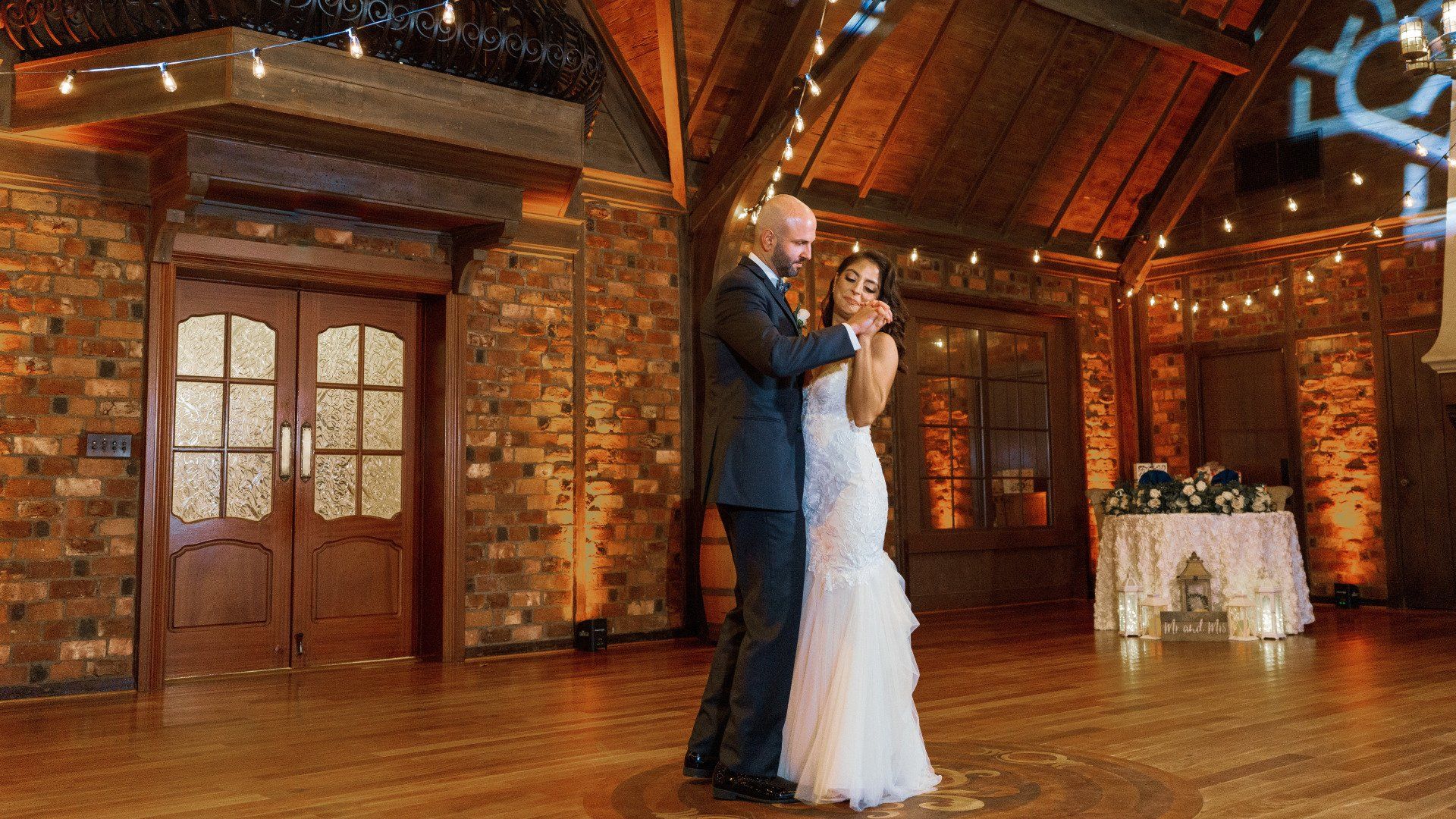 A bride and groom are dancing in a large room at their wedding reception.