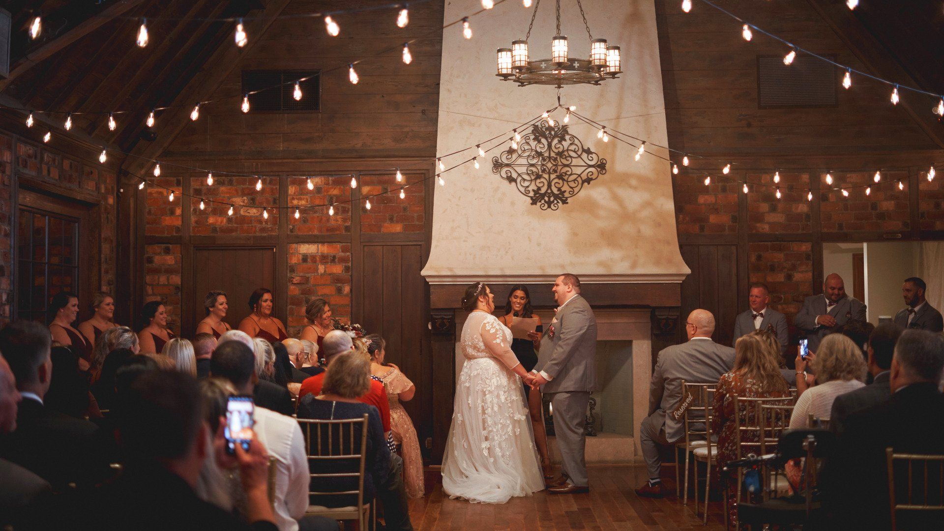 A bride and groom are holding hands during their wedding ceremony in front of a crowd of people.