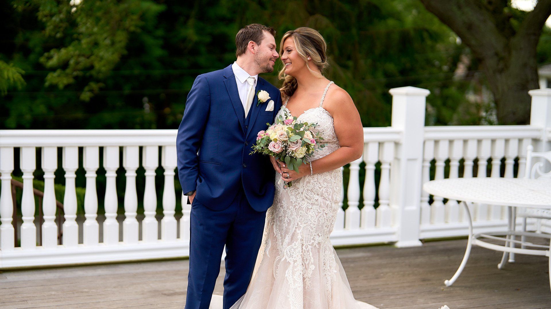 A bride and groom are standing next to each other on a deck.