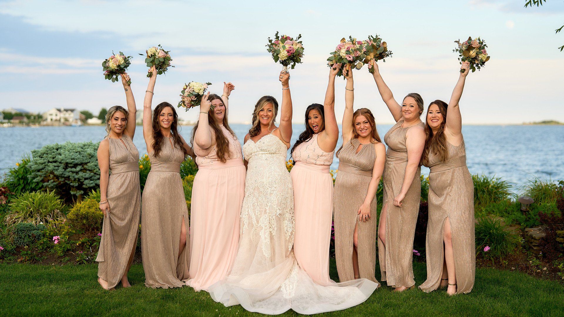 A bride and her bridesmaids are posing for a picture with their bouquets in the air.