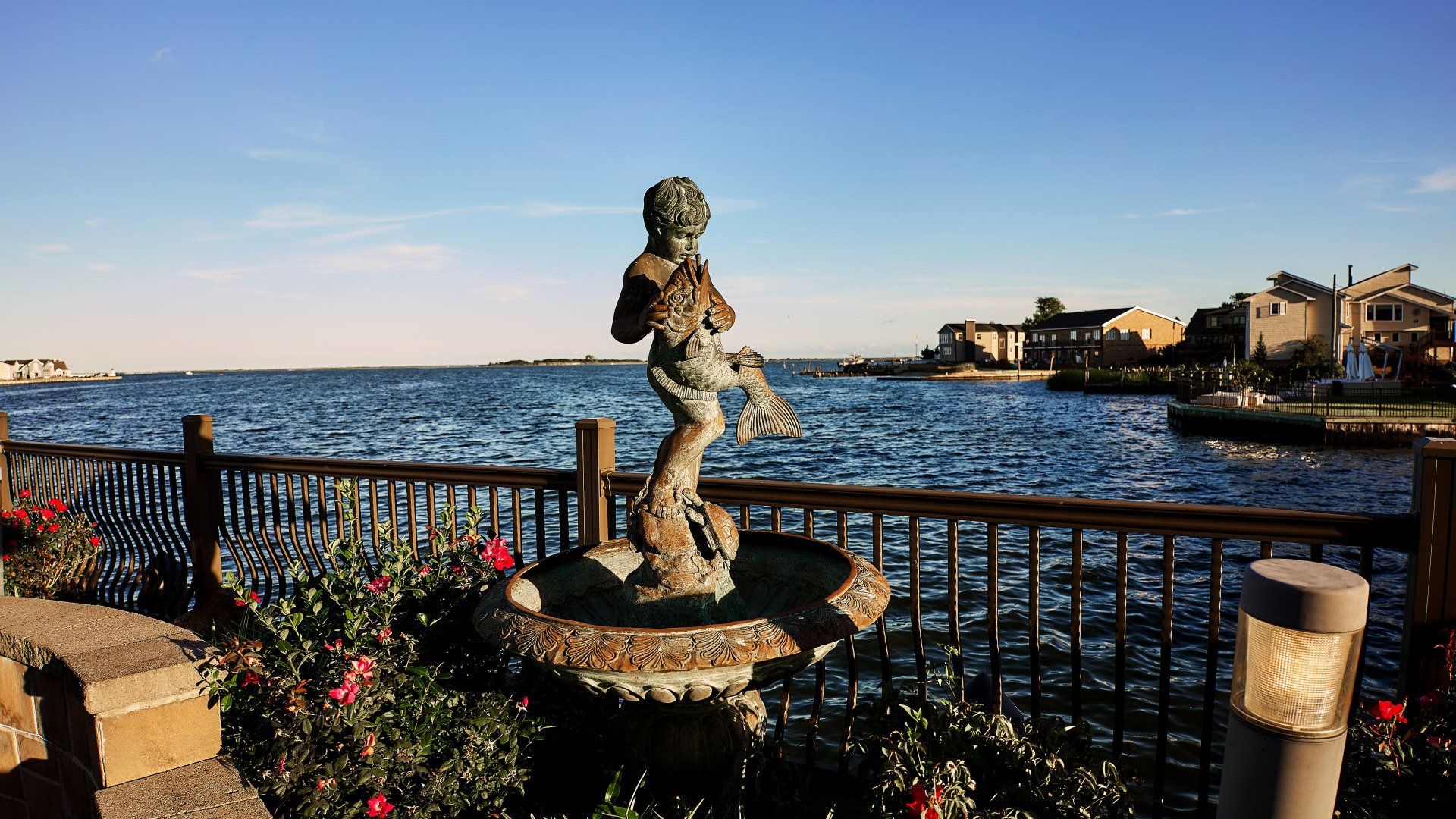 A fountain with a statue of a boy in front of a body of water