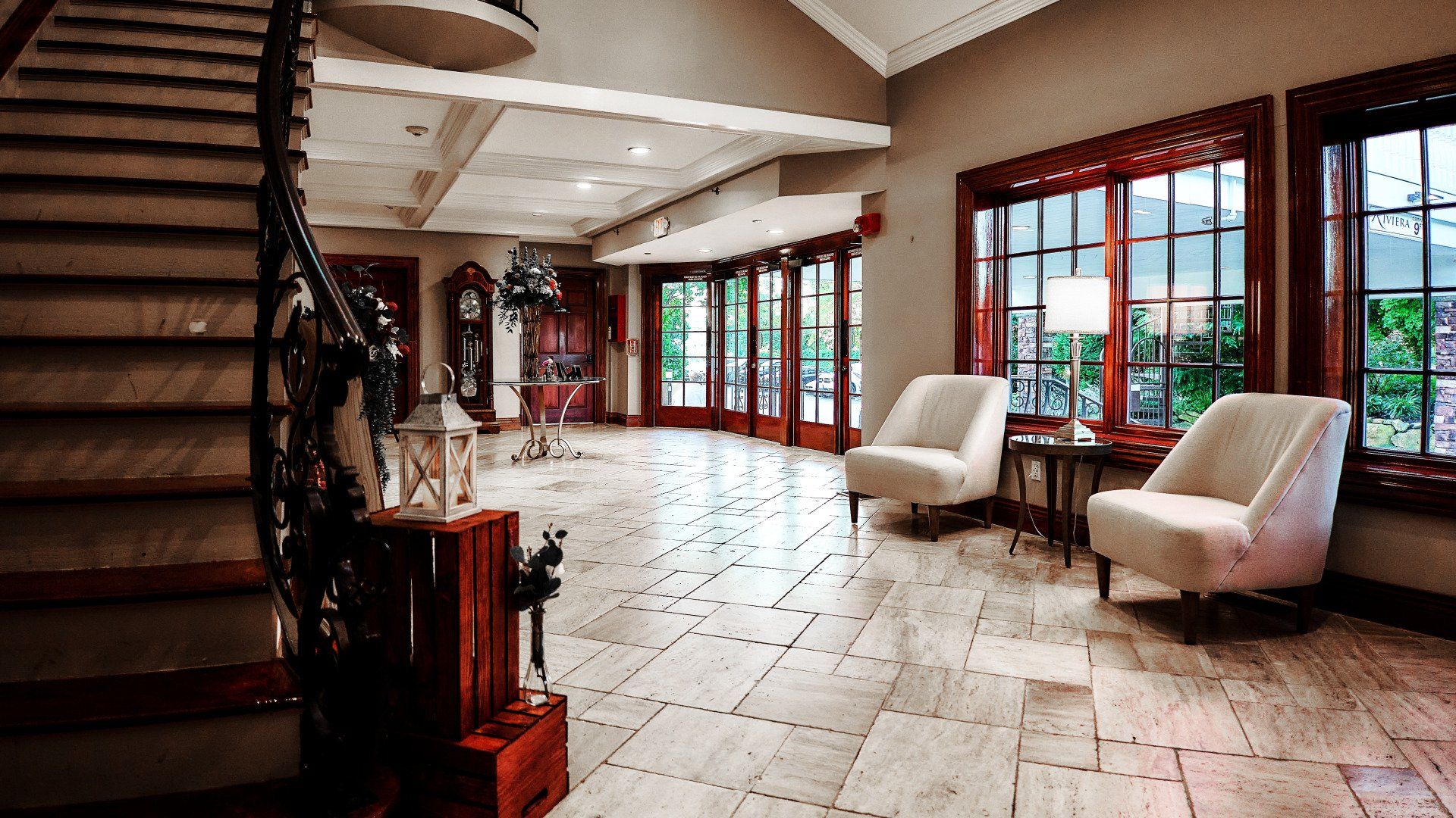 A large room with stairs , chairs , tables and windows.