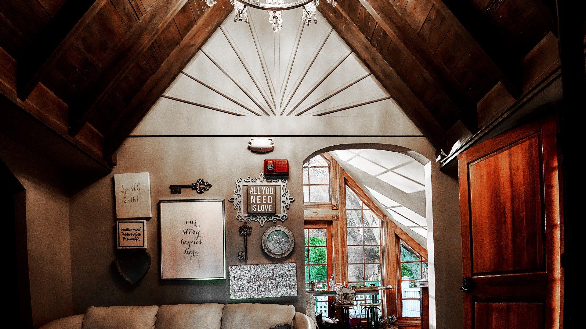 A living room with a couch and a chandelier hanging from the ceiling.