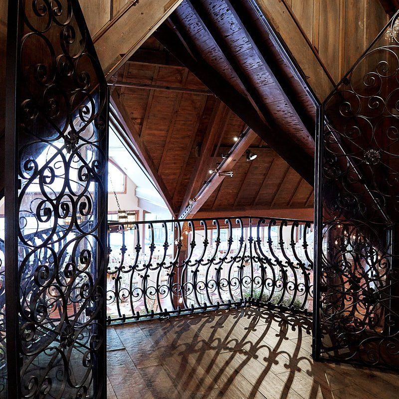 A balcony with a wrought iron railing and a wooden ceiling