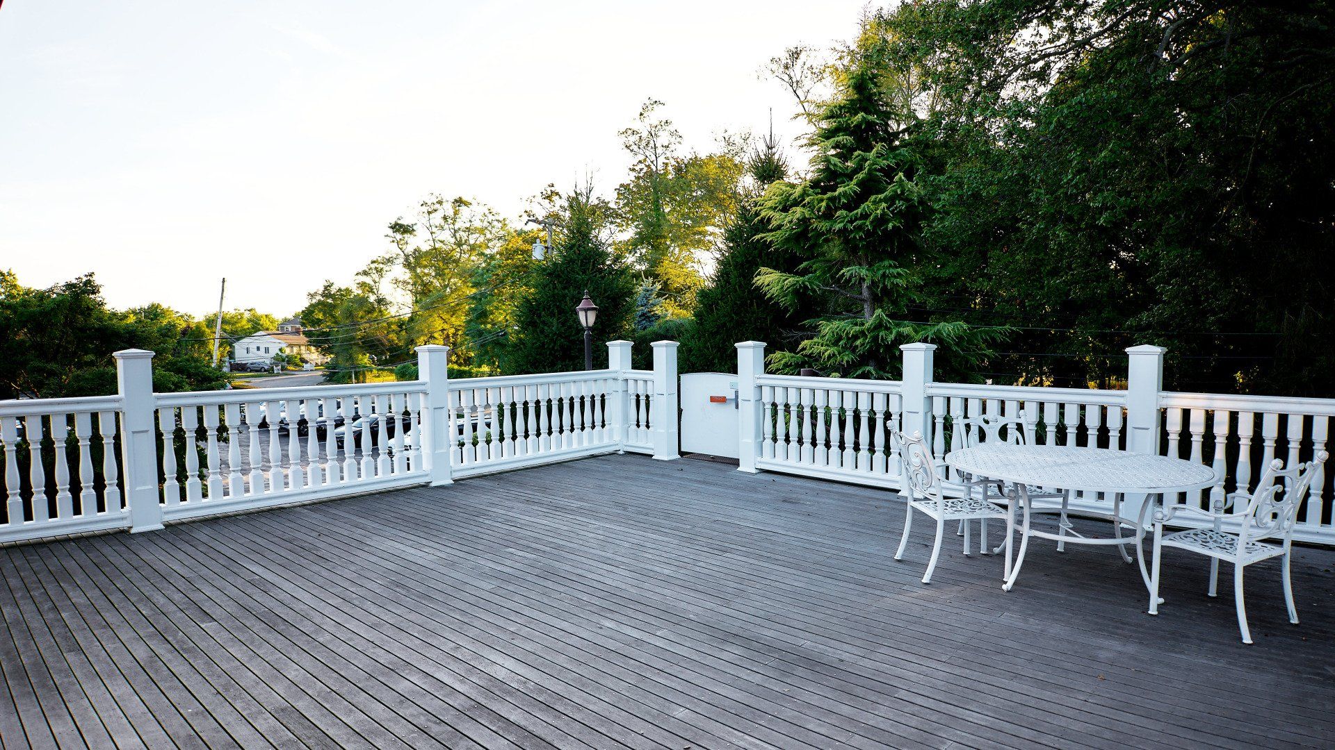 A wooden deck with a white railing and a table and chairs