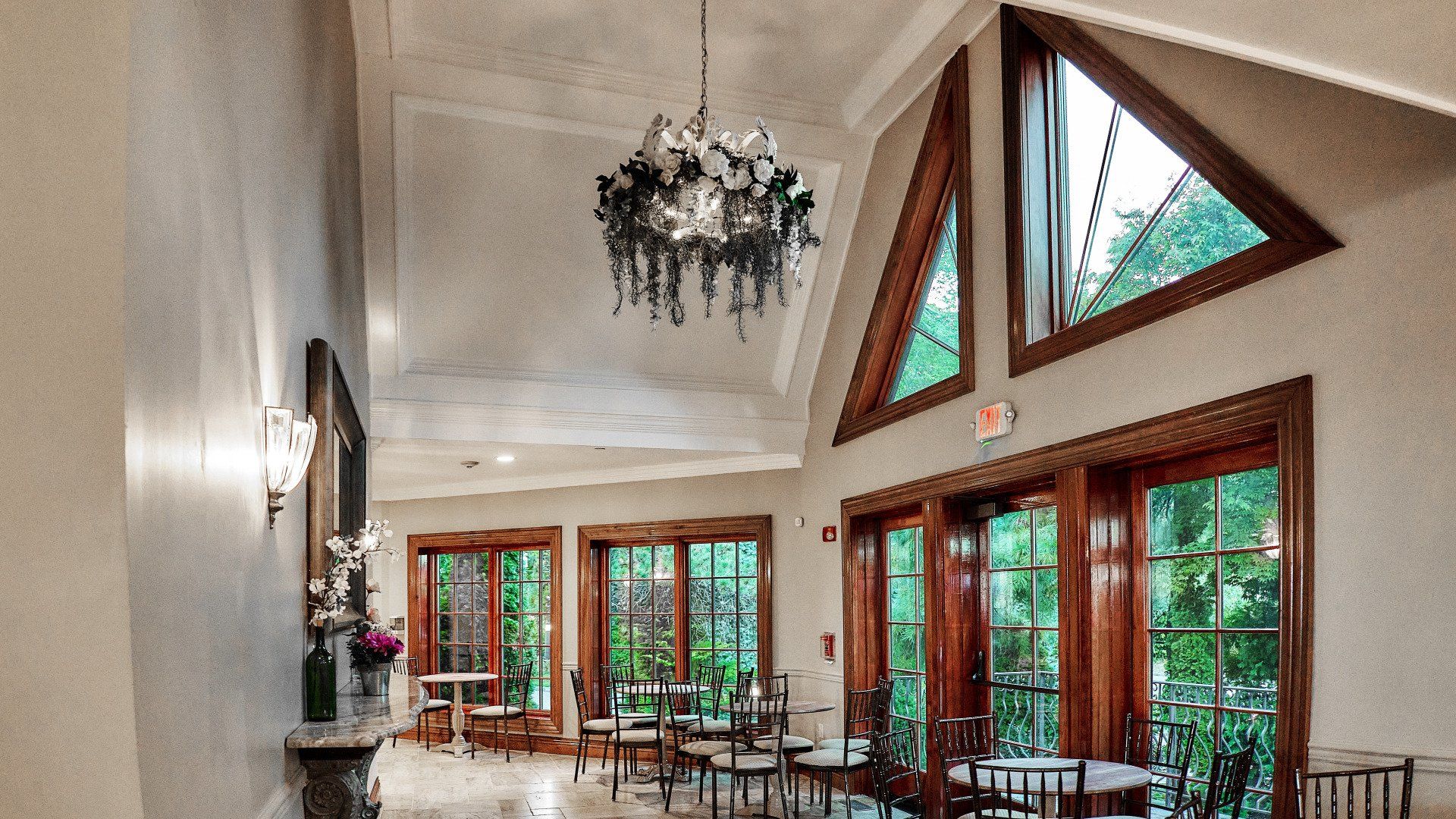 A large room with tables and chairs and a chandelier hanging from the ceiling