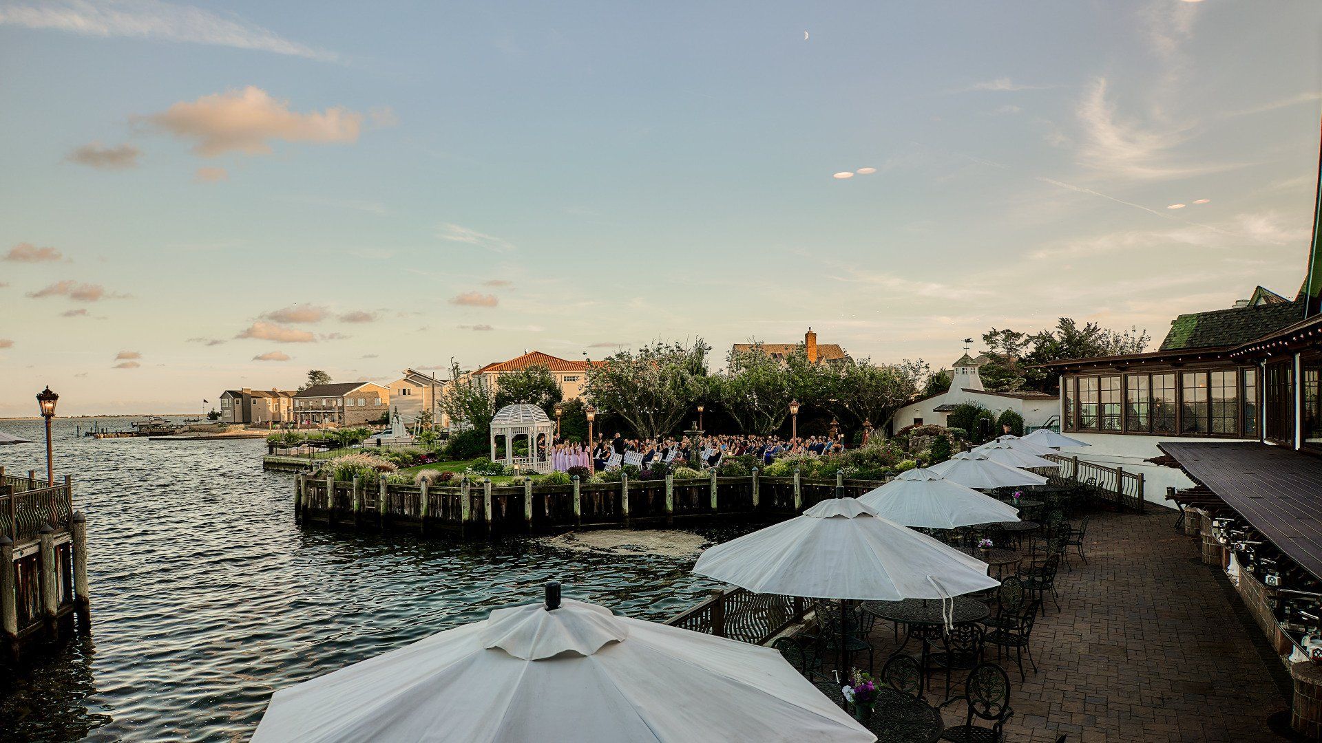 A row of white umbrellas are lined up in front of a body of water
