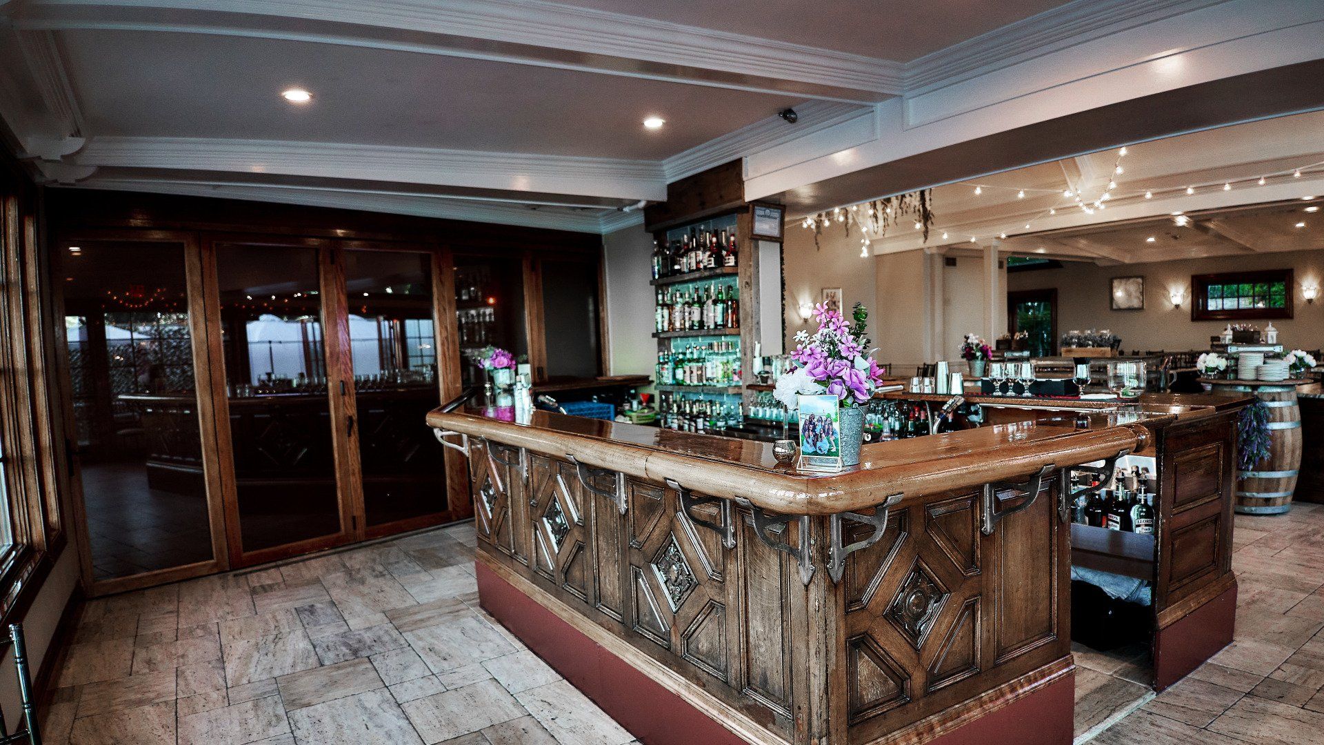 A large wooden bar in a restaurant with flowers on it.