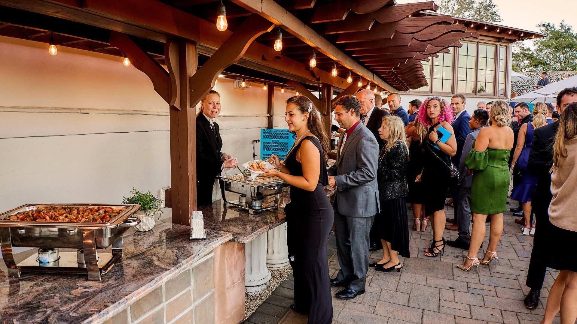 A group of people are standing around a buffet line at a wedding reception.