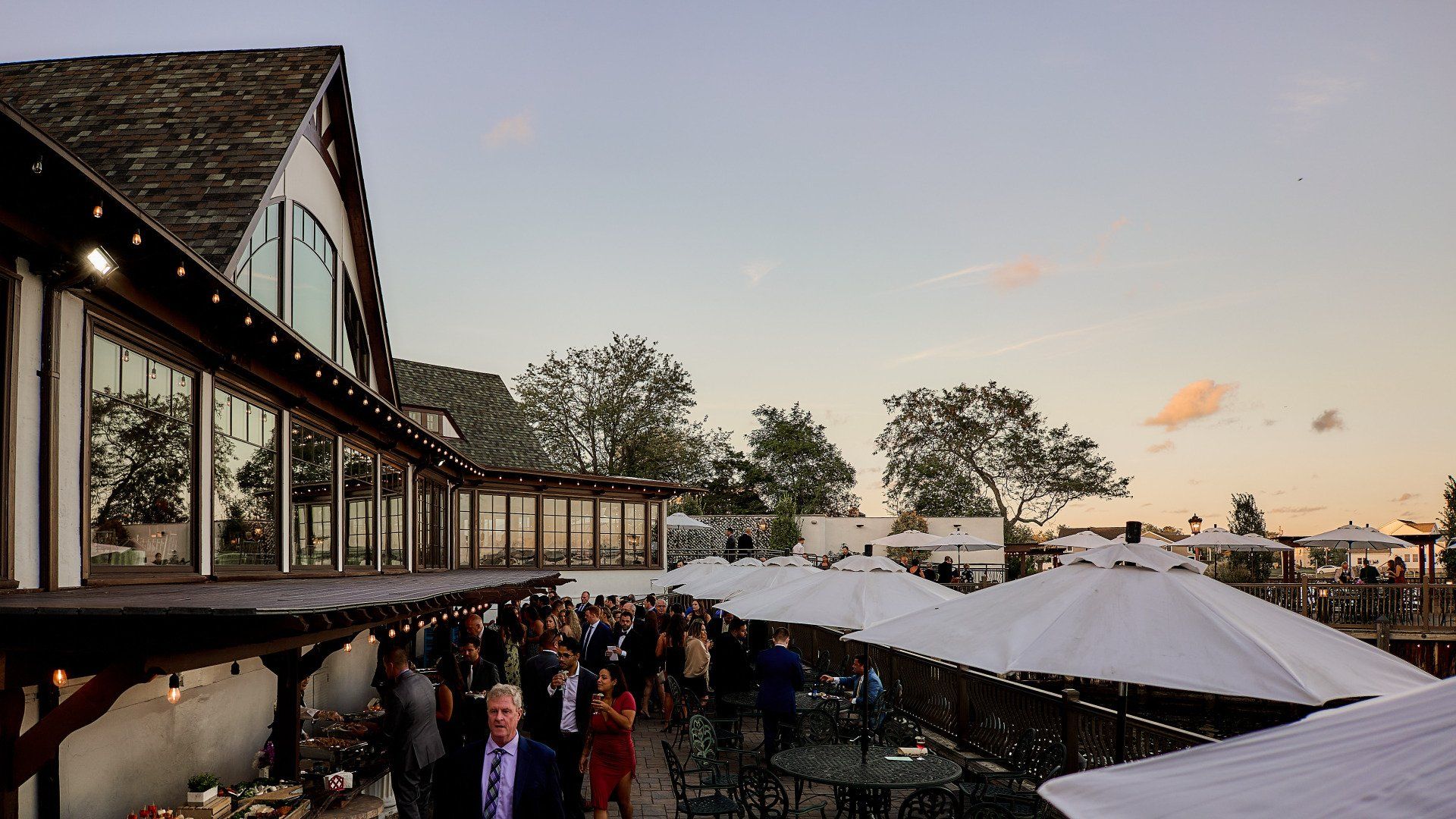 A group of people are standing outside of a building with umbrellas.