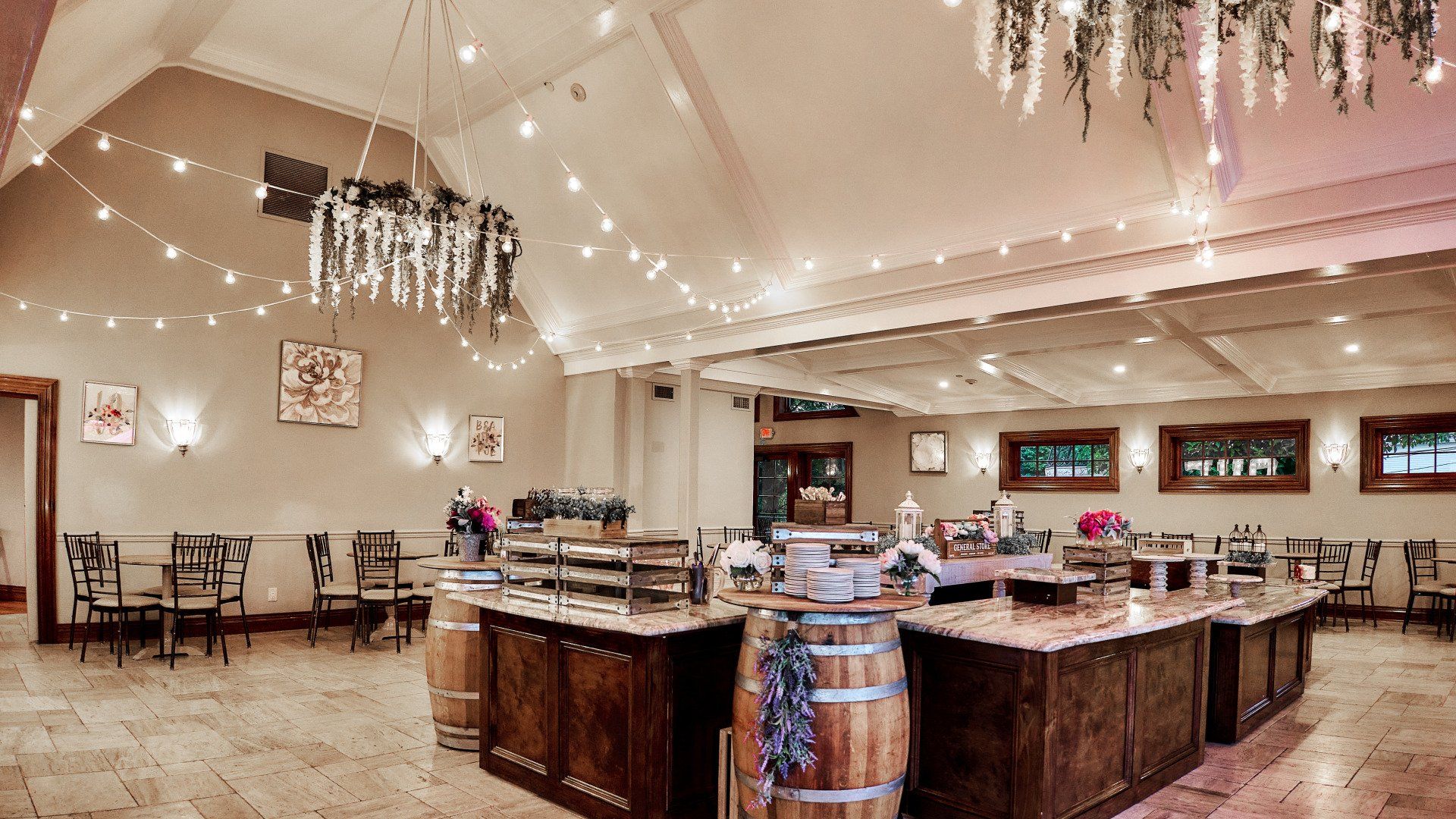 A large room with a lot of tables and chairs and a chandelier hanging from the ceiling.