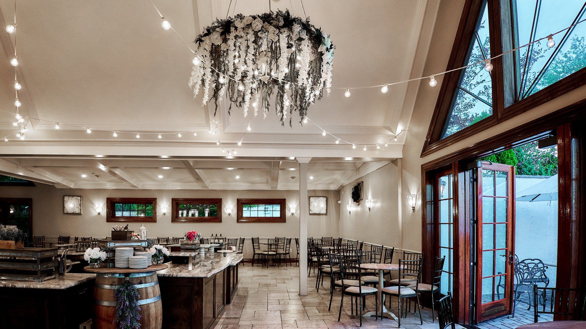 A large room with tables and chairs and a chandelier hanging from the ceiling.