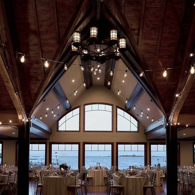 A large room with tables and chairs and a chandelier hanging from the ceiling