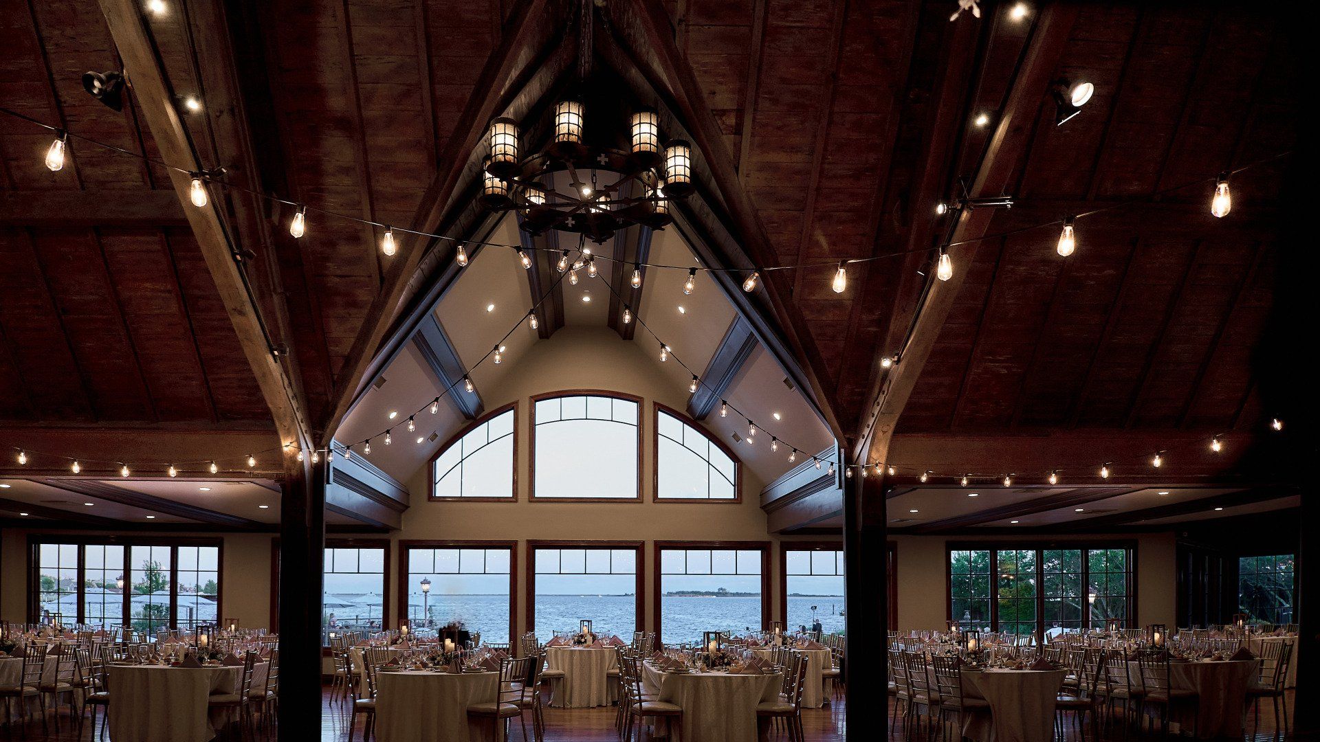 A large room with tables and chairs and a chandelier hanging from the ceiling.
