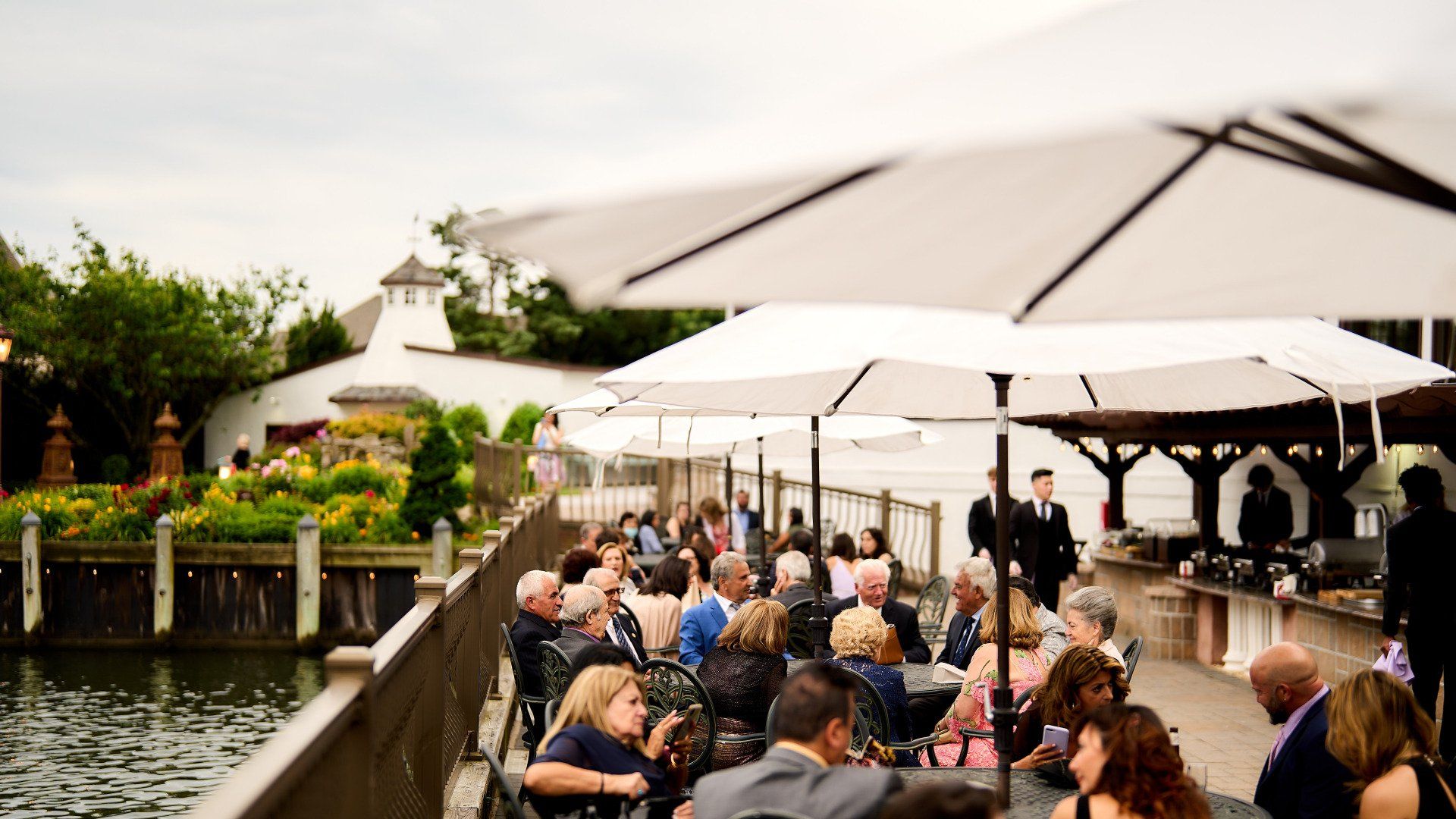 A group of people are sitting under umbrellas near a body of water.