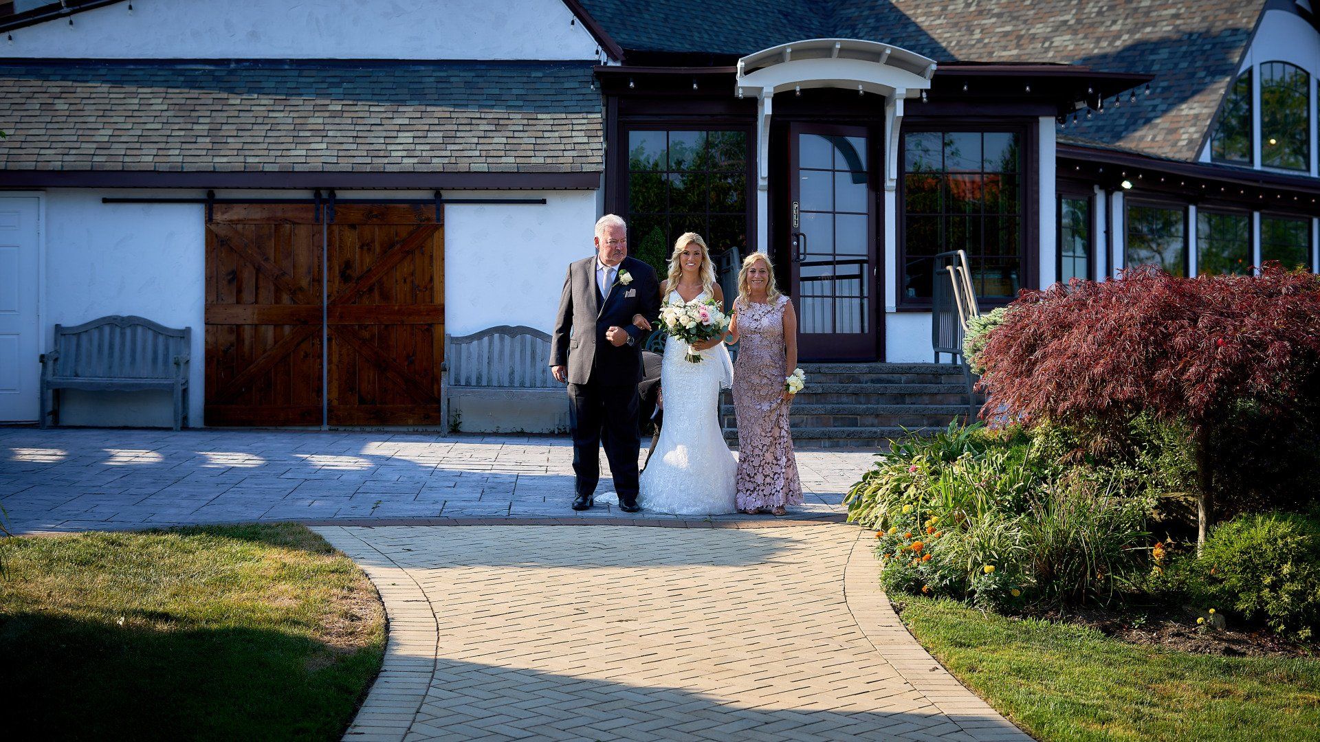 A bride is walking down the aisle with her father and mother.