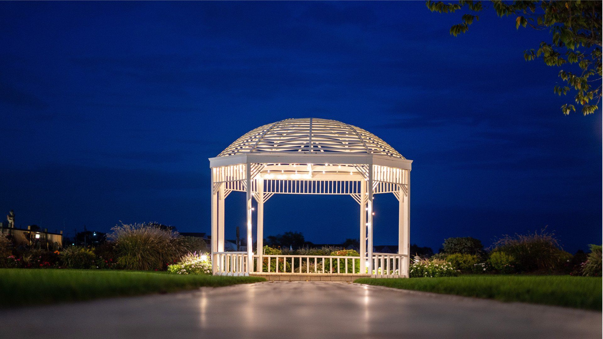 A white gazebo is lit up at night in a park.