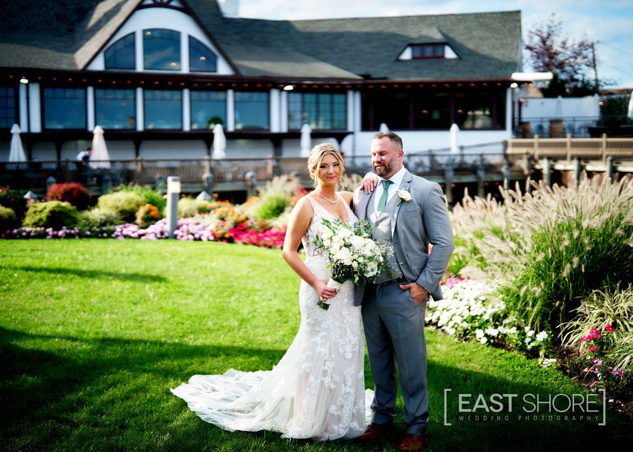 A bride and groom are posing for a picture in front of a large building.