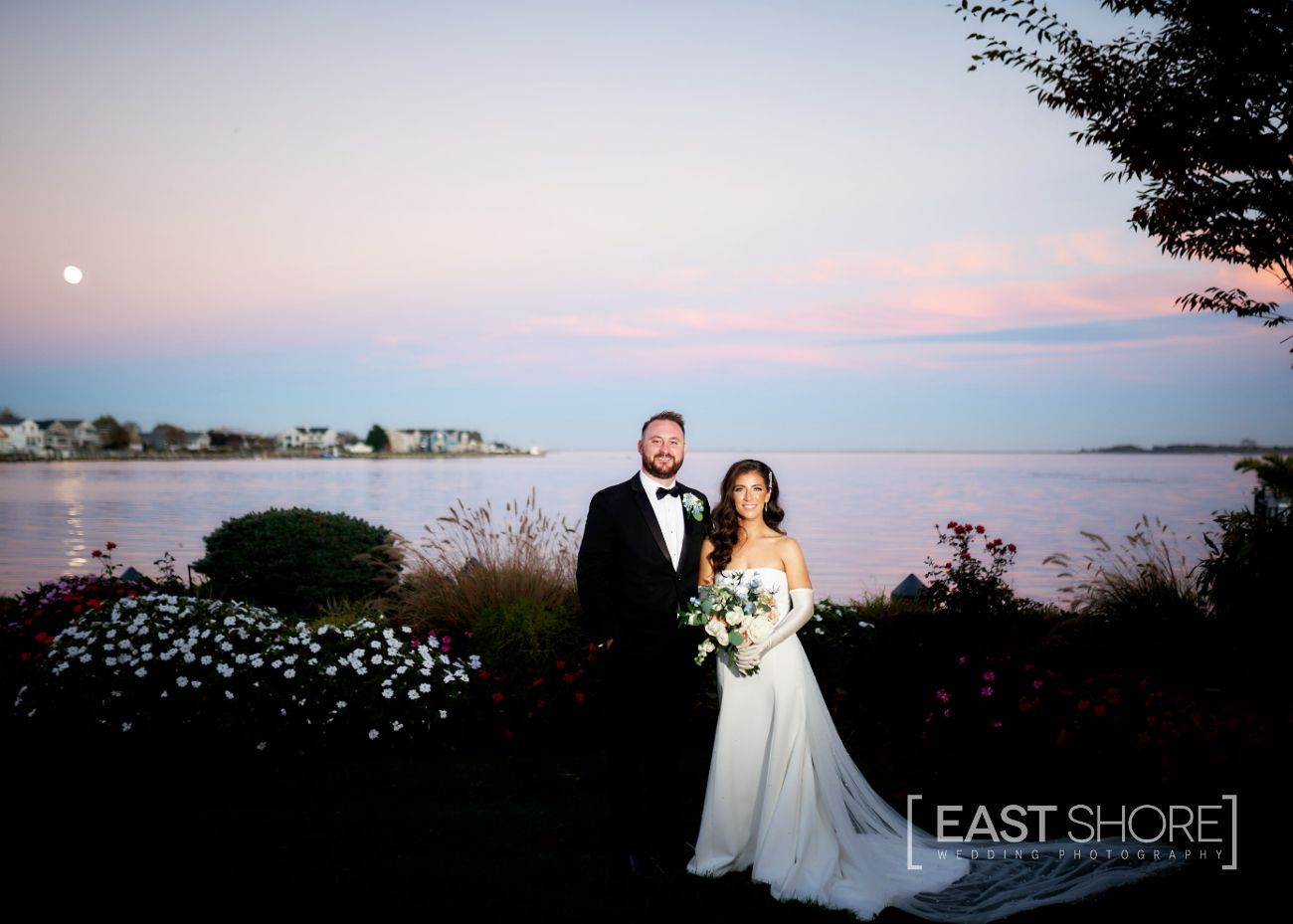 A bride and groom standing in front of a body of water with east shore written on the bottom