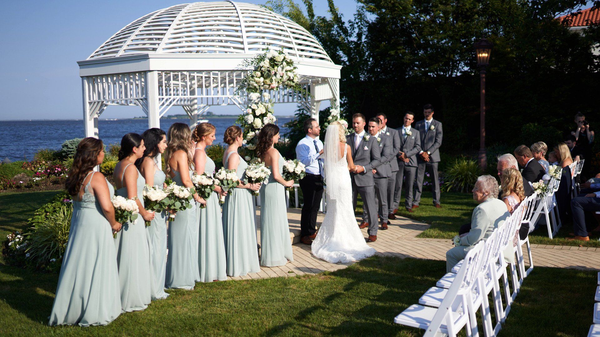 A bride and groom are getting married in front of a gazebo.