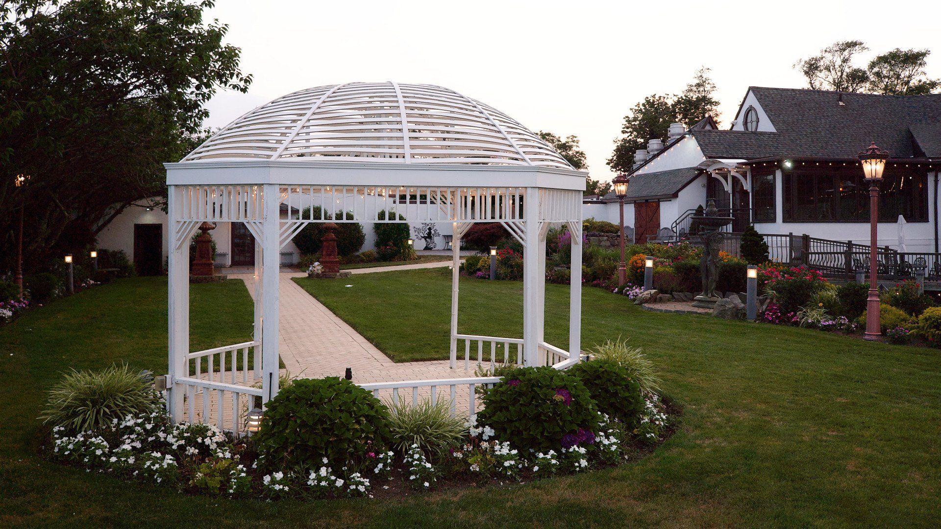 A white gazebo is in the middle of a lush green field