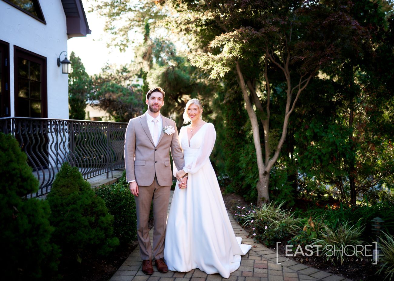 A bride and groom are posing for a picture in front of a house.