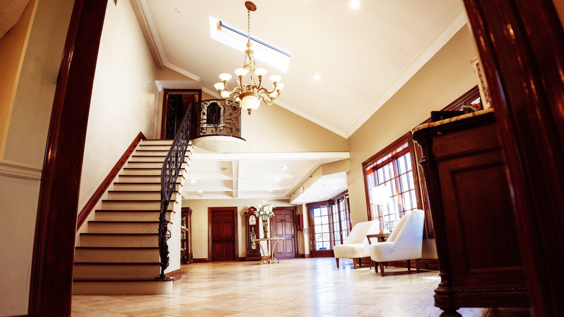 A hallway with stairs and a chandelier hanging from the ceiling