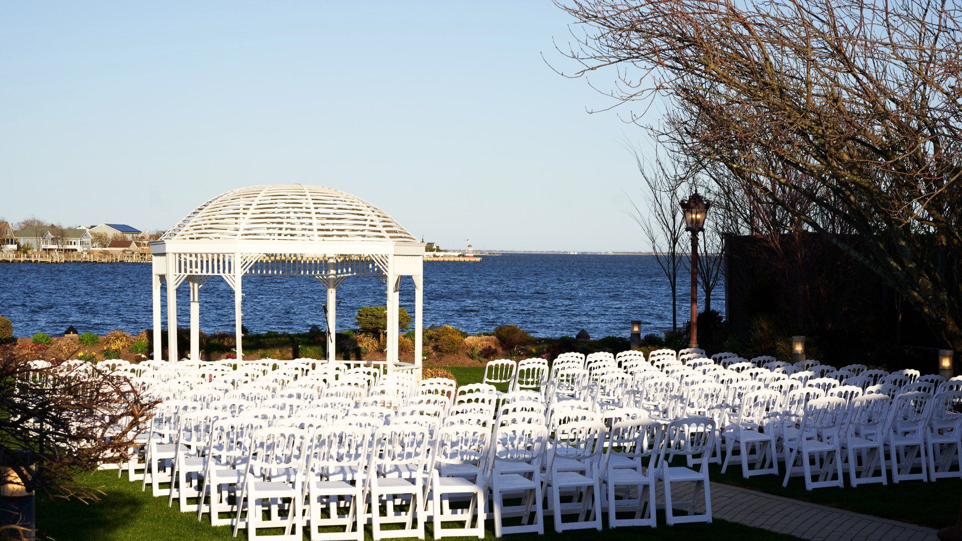 Rows of white chairs are lined up in front of a gazebo overlooking the ocean