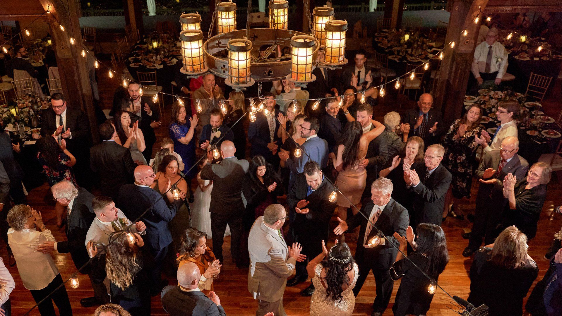 A large group of people are dancing at a wedding reception.