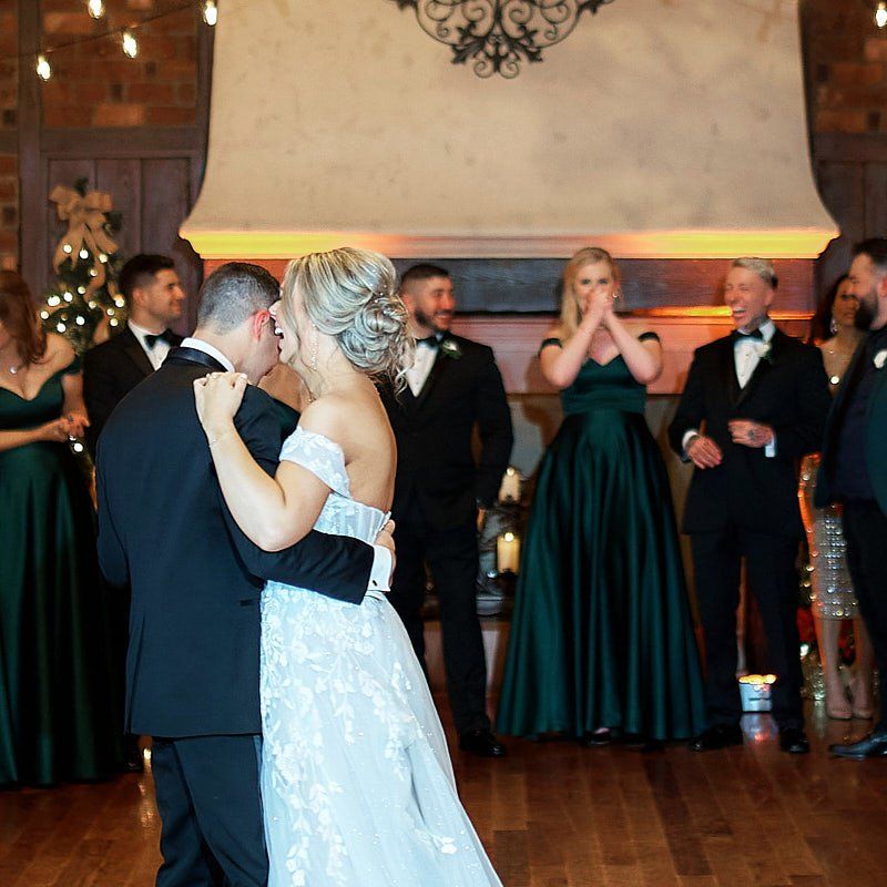 A bride and groom are dancing in front of their wedding party