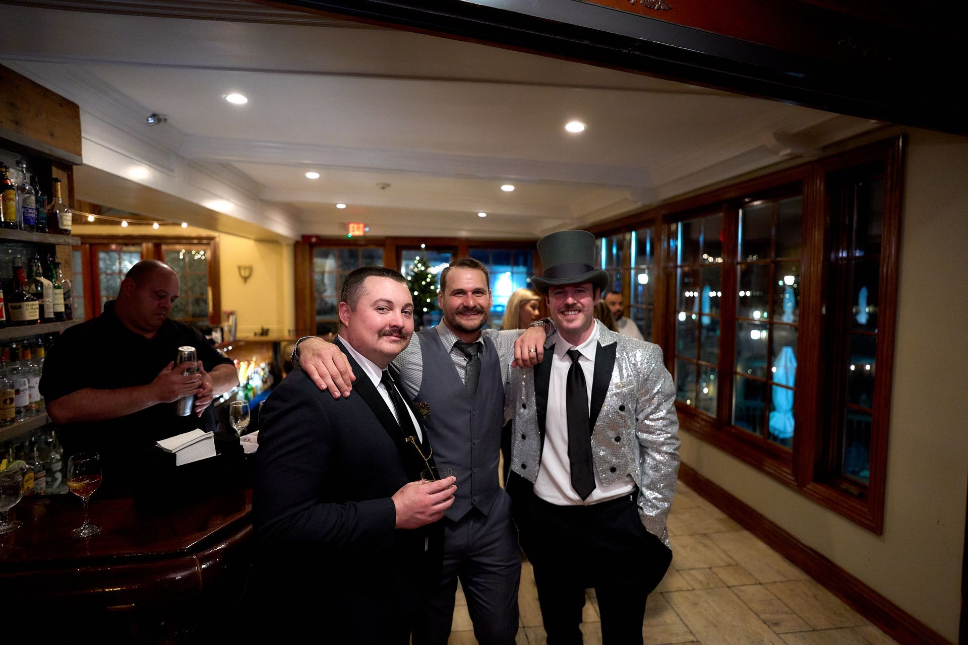 Three men in suits and top hats are posing for a picture in a hallway.