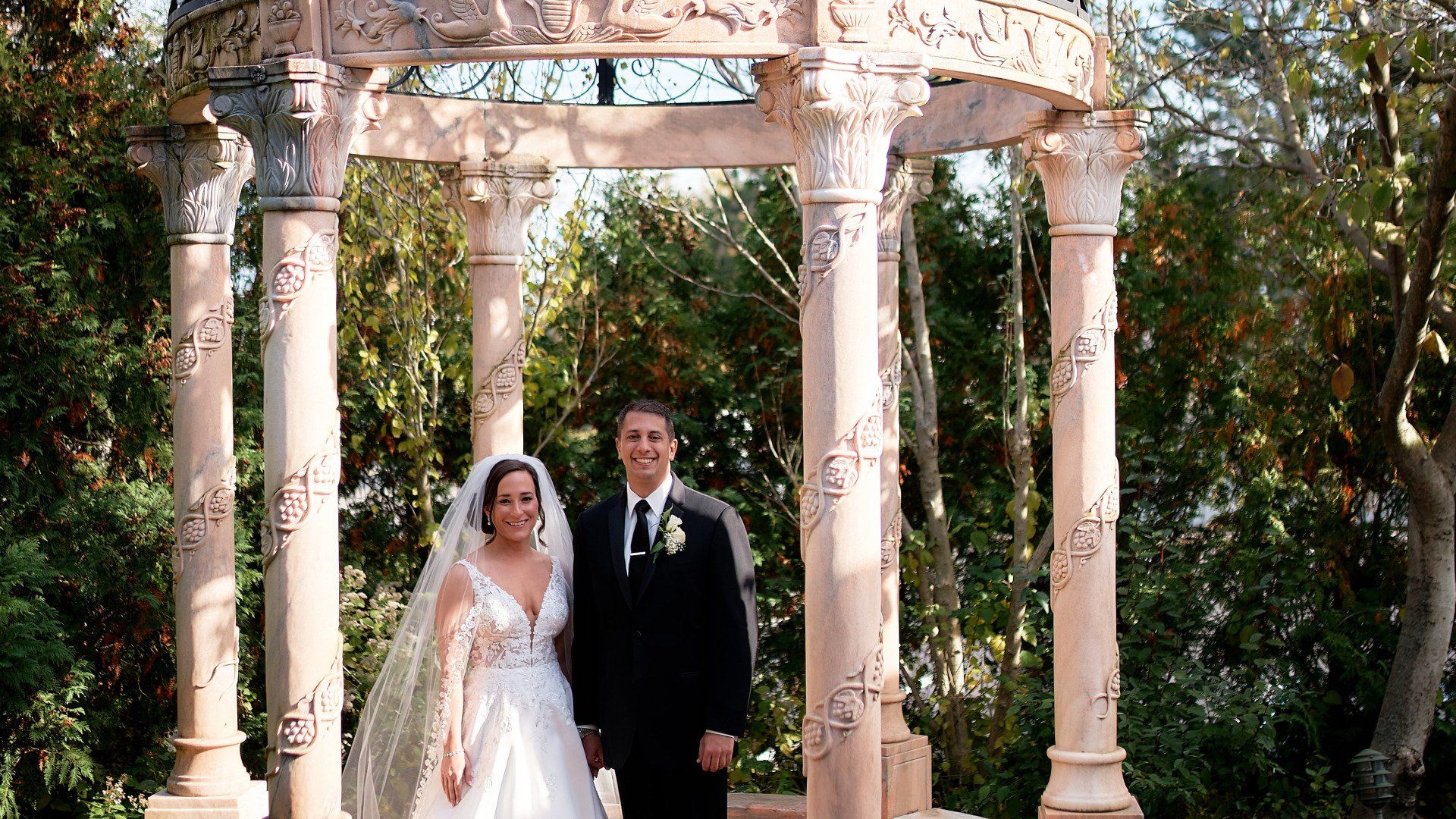 A bride and groom are posing for a picture under a gazebo.