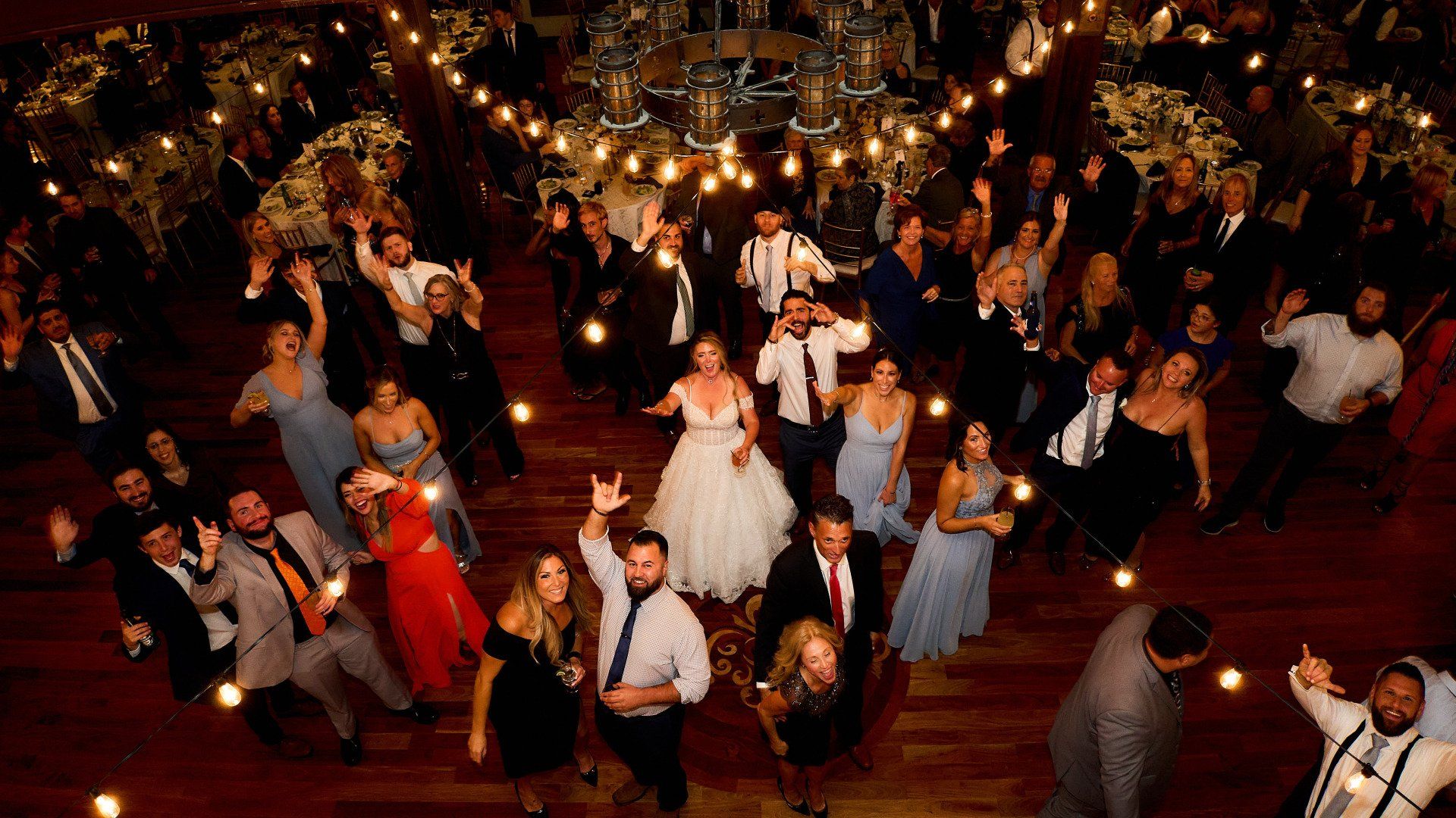A large group of people are dancing at a wedding reception.