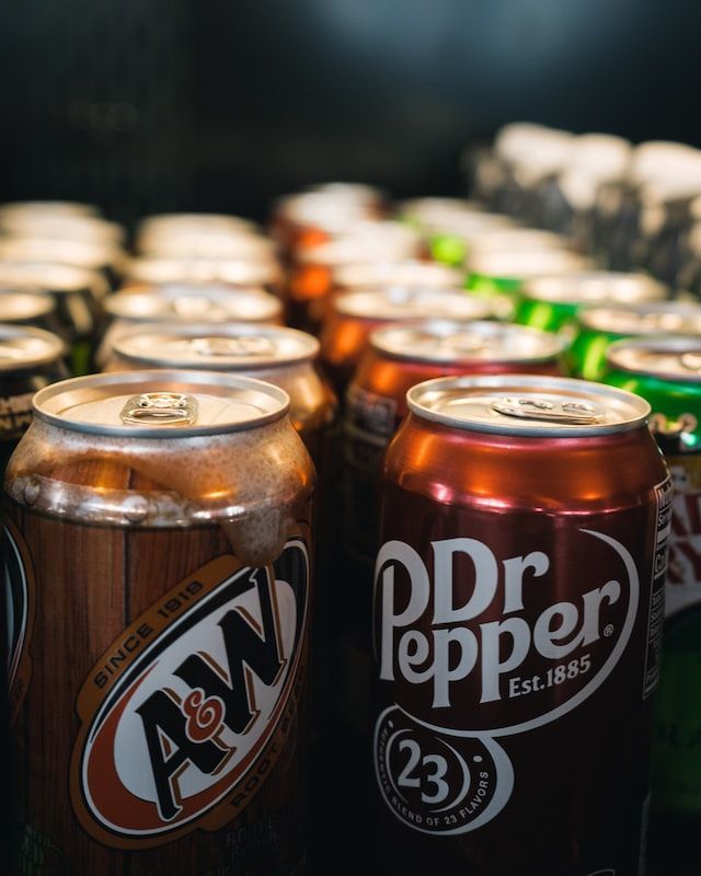 A can of dr pepper sits next to a can of a&w