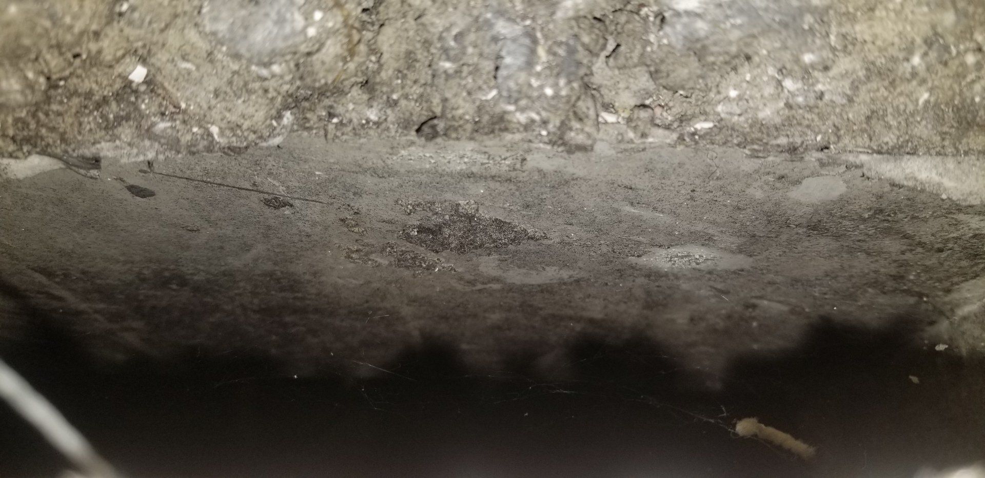 Close-up of a rough, textured gray surface, with a dark, shadowy bottom.