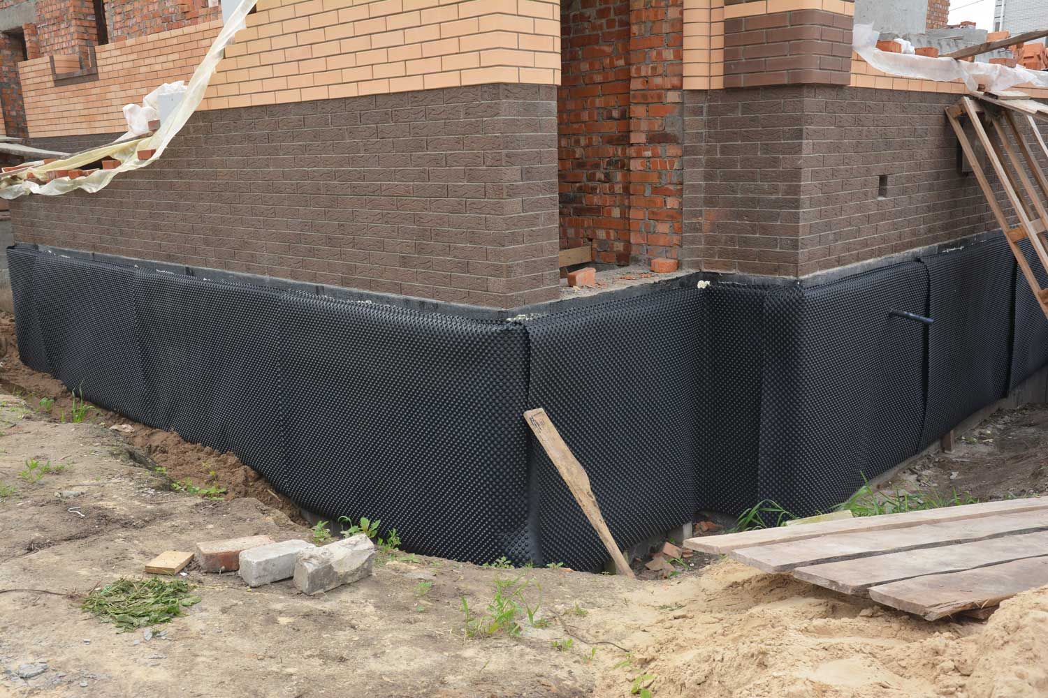 lack waterproof membrane installed around brick house foundation during construction.