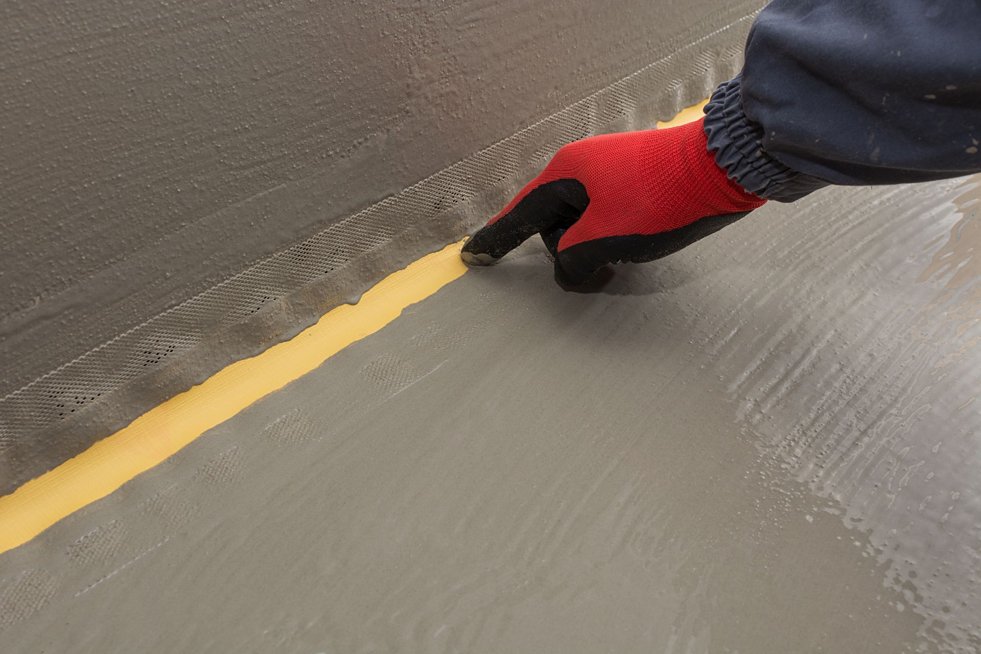 A worker shows the elastic part of a waterproof strip in a waterproofing system. A worker shows the elastic part of a waterproof strip in a waterproofing system.