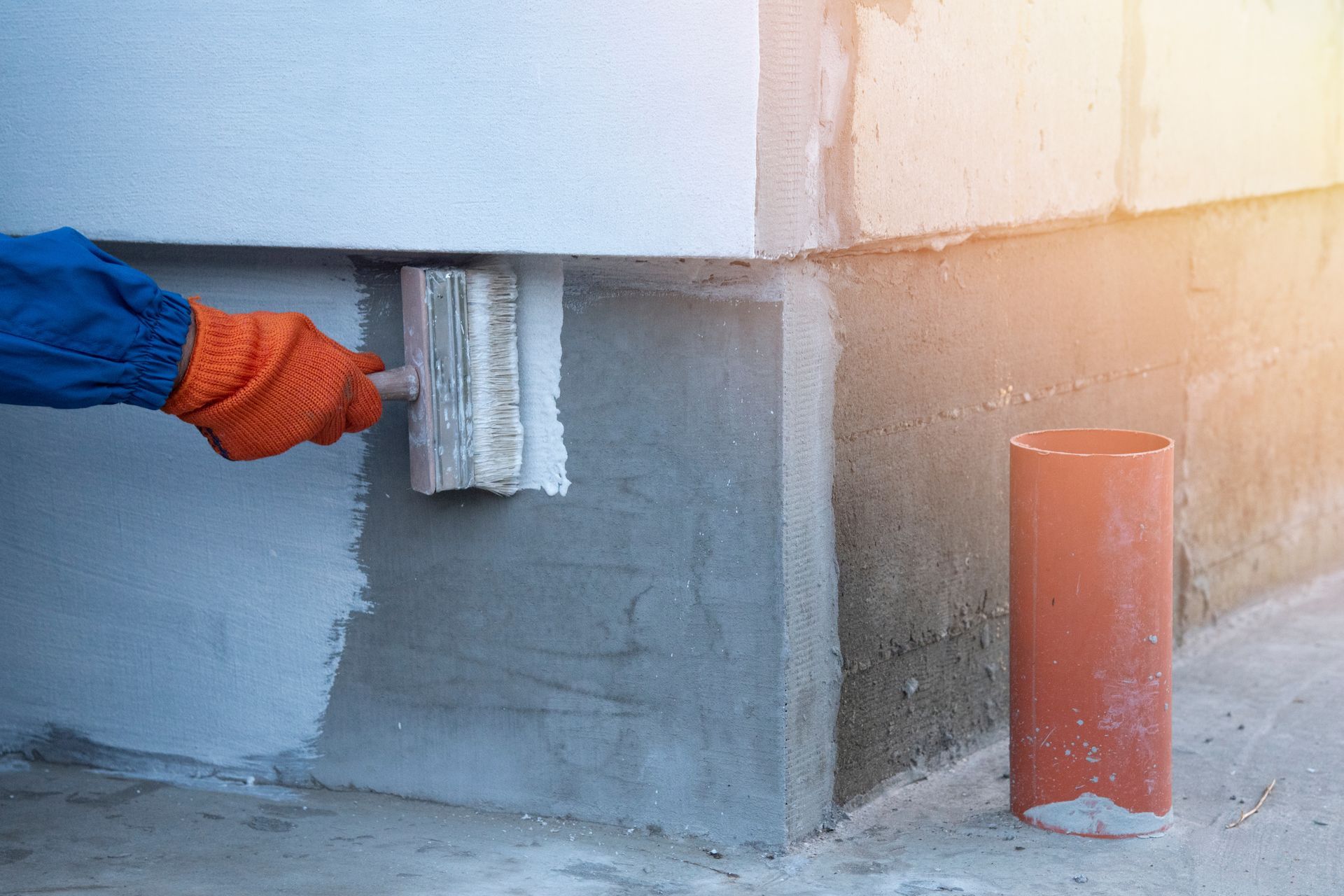 Waterproofing contractor priming exterior house foundation.