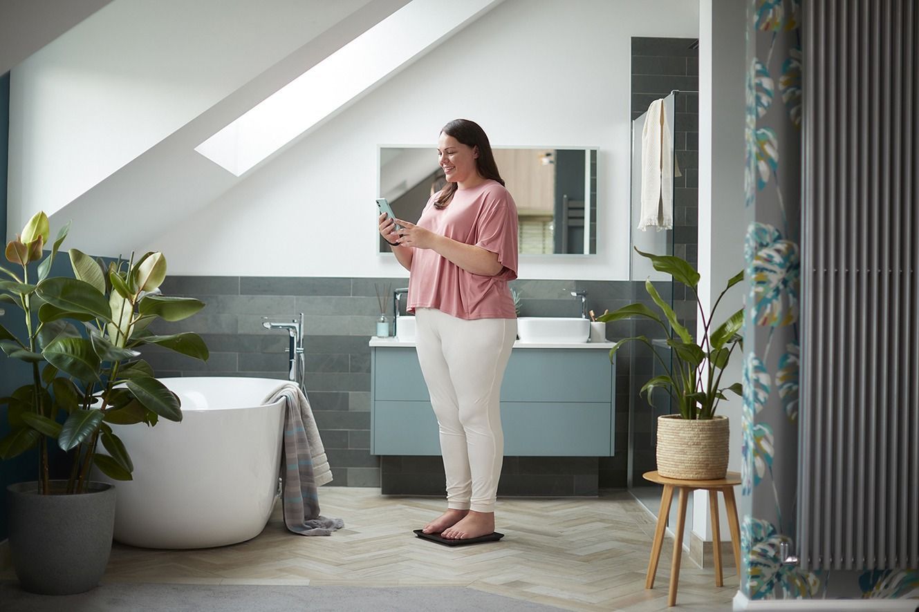 smiling woman standing in the bathroom with the smartphone