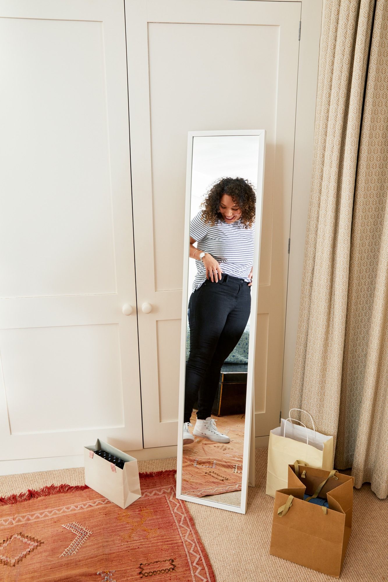 reflection in the mirror of a smiling woman trying on jeans
