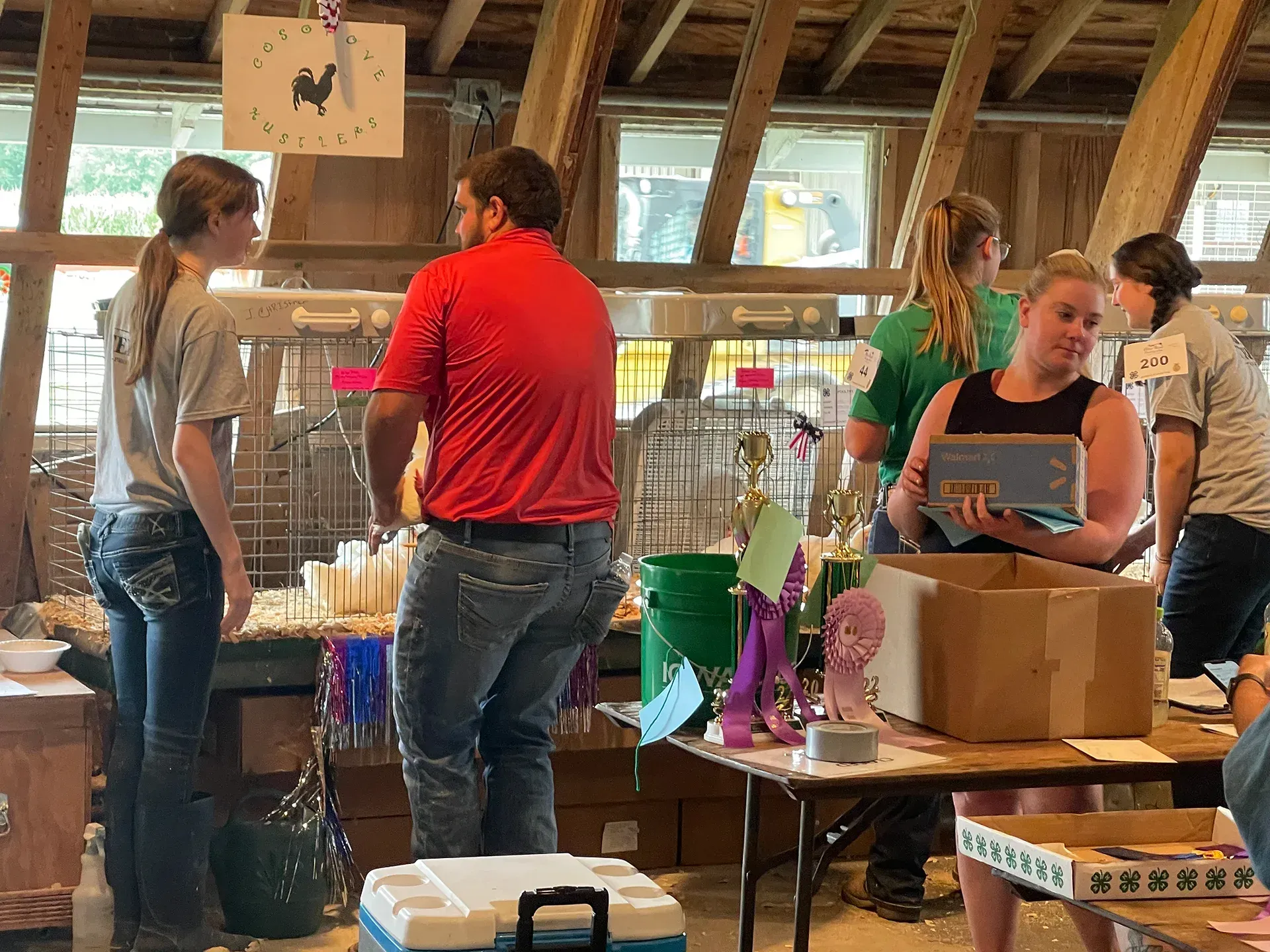 People sorting items at a community event inside a barn-like room with tables and boxes