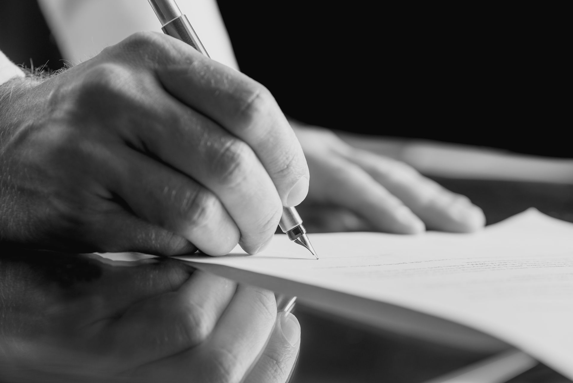 A person is writing on a piece of paper with a pen.